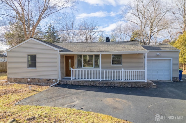 single story home with aphalt driveway, a chimney, covered porch, crawl space, and a garage