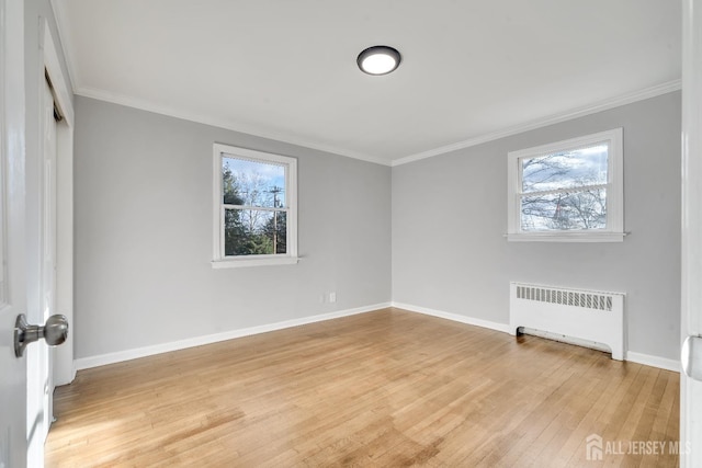 spare room with baseboards, light wood finished floors, radiator heating unit, and crown molding