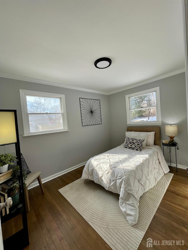 bedroom with ornamental molding, hardwood / wood-style floors, and baseboards