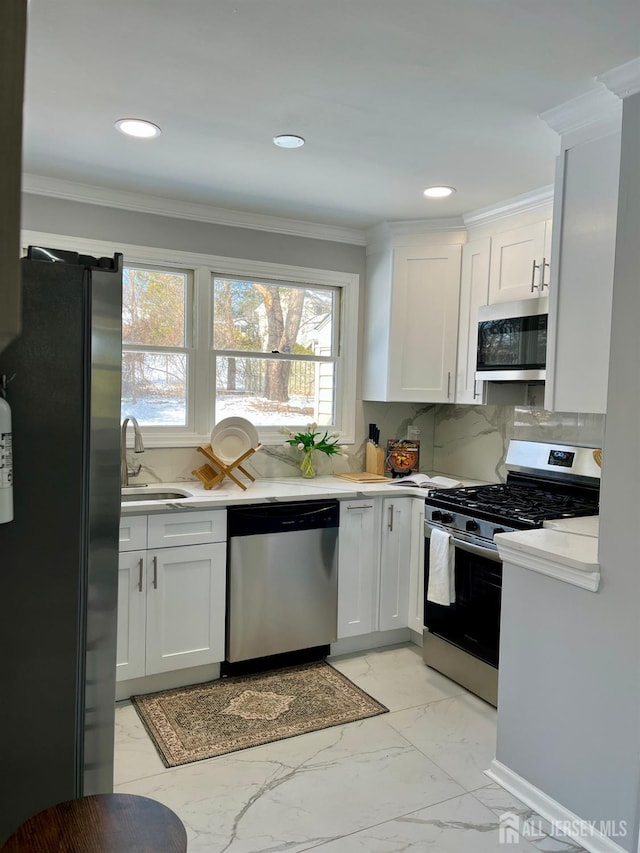 kitchen featuring appliances with stainless steel finishes, a sink, decorative backsplash, and ornamental molding