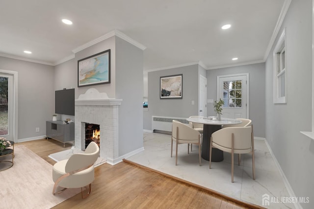 dining area with a fireplace, radiator heating unit, light hardwood / wood-style floors, and ornamental molding