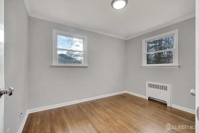 unfurnished room with ornamental molding, baseboards, radiator heating unit, and wood finished floors