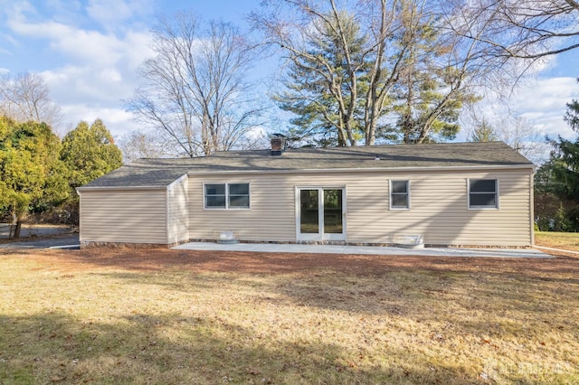 rear view of property with a chimney, a lawn, and a patio area