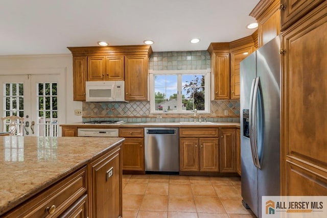 10 Lauri Ln, Middlesex, NJ 08846 - kitchen featuring appliances with stainless steel finishes, a sink, brown cabinetry, light tile patterned flooring, and healthy amount of natural light