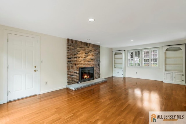 10 Lauri Ln, Middlesex, NJ 08846 - unfurnished living room featuring wood finished floors, a brick fireplace, recessed lighting, baseboards, and built in shelves