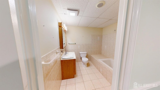 53 Kirschman Dr, Old Bridge, NJ 07747 - bathroom with tile patterned flooring, a relaxing tiled tub, vanity, a drop ceiling, and tile walls
