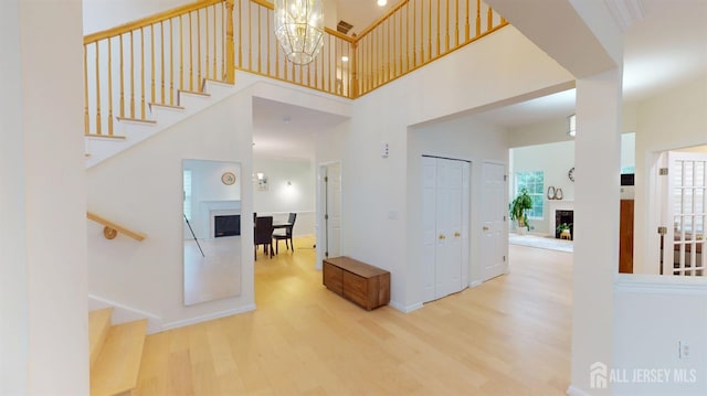 53 Kirschman Dr, Old Bridge, NJ 07747 - foyer featuring a fireplace, stairs, wood finished floors, a towering ceiling, and a chandelier
