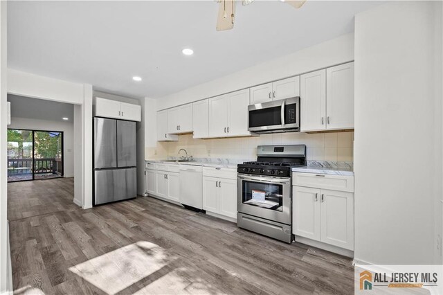 kitchen with stainless steel appliances, hardwood / wood-style floors, decorative backsplash, and white cabinets