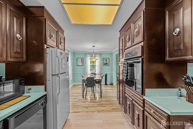 kitchen featuring dark brown cabinetry, light hardwood / wood-style flooring, decorative light fixtures, black appliances, and crown molding