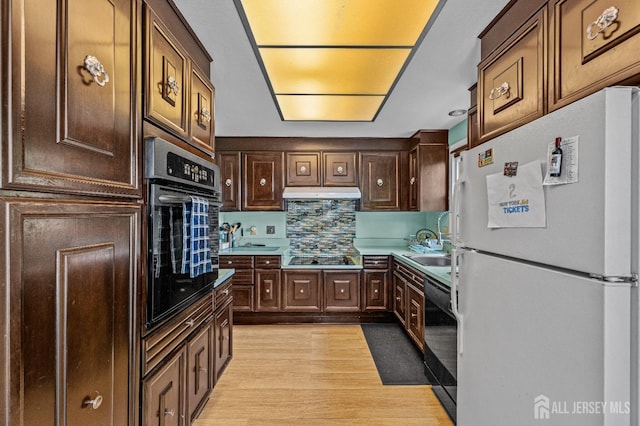 kitchen featuring sink, light wood-type flooring, black appliances, dark brown cabinets, and decorative backsplash