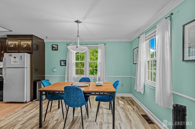 dining area with ornamental molding and light wood-type flooring