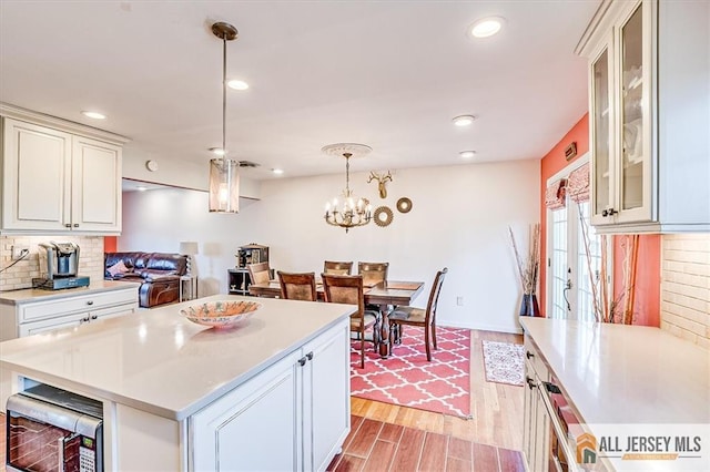 6 Mockingbird Rd, Edison, NJ 08820 - kitchen with light countertops, decorative backsplash, light wood-style flooring, hanging light fixtures, and glass insert cabinets