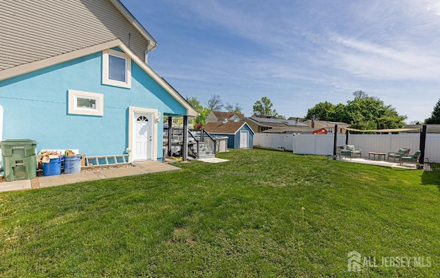 view of yard featuring a storage shed, fence, an outbuilding, and a patio area