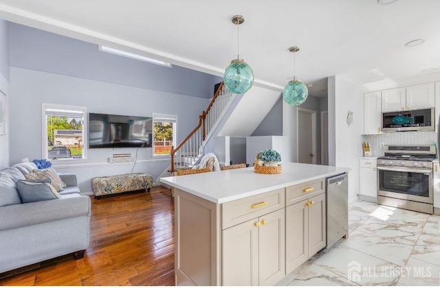 kitchen with decorative backsplash, open floor plan, a center island, light countertops, and appliances with stainless steel finishes