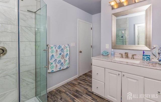 full bathroom featuring vanity, a stall shower, baseboards, and wood finished floors