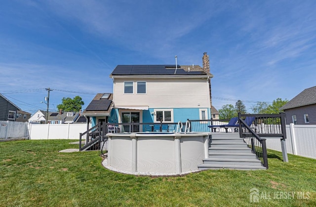 back of house with stairs, a chimney, a deck, and solar panels