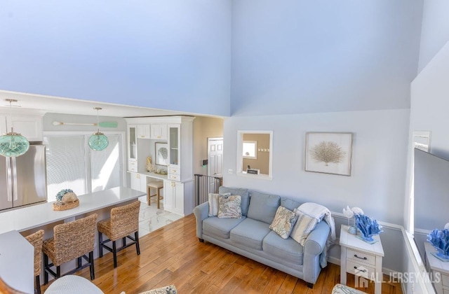 living area with light wood-style floors and high vaulted ceiling
