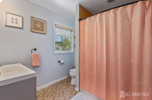 bathroom featuring baseboards, toilet, and vanity