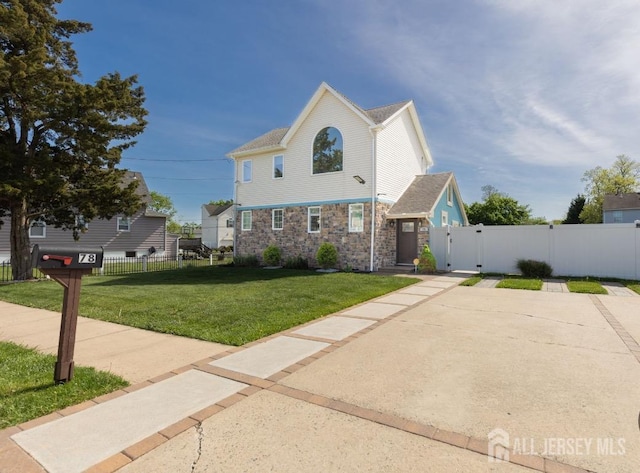 view of front of home with fence, a gate, stone siding, and a front yard