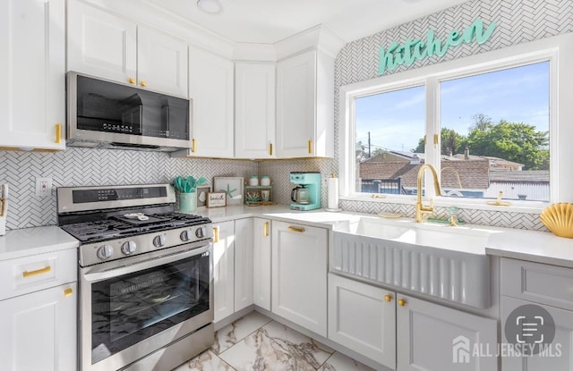 kitchen featuring a sink, light countertops, marble finish floor, and appliances with stainless steel finishes