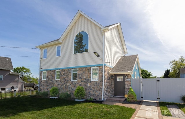 view of front of property featuring a gate, a front lawn, fence, and stone siding