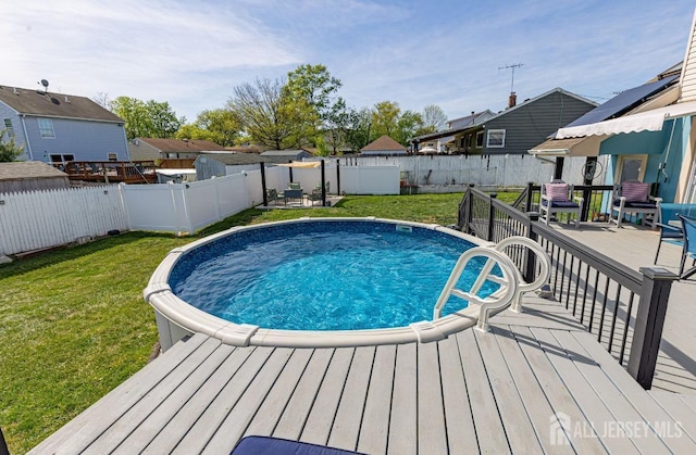 view of swimming pool featuring a fenced backyard, a yard, and a deck