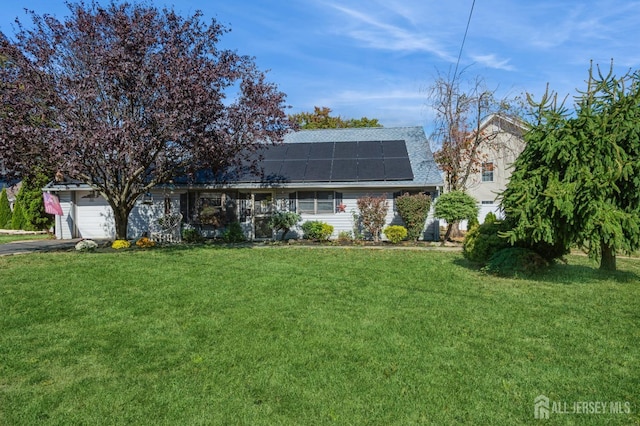 view of front of house with a front yard, solar panels, and a garage