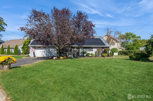 view of front of home with solar panels, a garage, and a front lawn