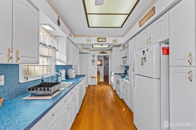 kitchen featuring white appliances, white cabinets, sink, light wood-type flooring, and tasteful backsplash