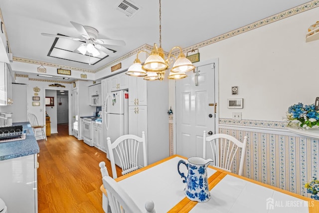 dining area with ceiling fan with notable chandelier and light hardwood / wood-style floors