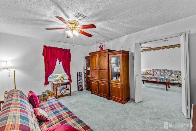 living area with light carpet, ceiling fan, and a textured ceiling