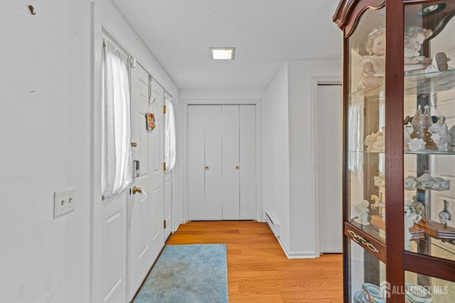 entryway featuring light hardwood / wood-style floors, a textured ceiling, and a baseboard radiator