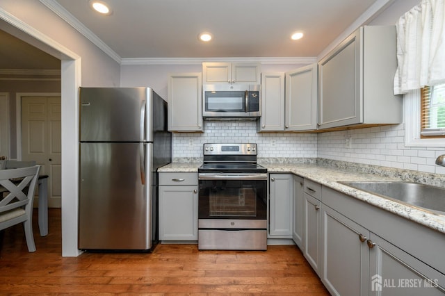439 Old Main St, Franklin, NJ 08802 - kitchen featuring stainless steel appliances, crown molding, light wood-style floors, decorative backsplash, and gray cabinets