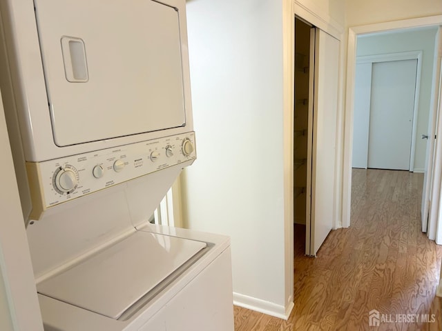 4424 Sayre Dr, Plainsboro, NJ 08540 - laundry room with light wood-style flooring, stacked washer and clothes dryer, and baseboards