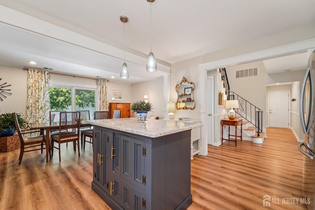 35 Poet Dr, Matawan, NJ 07747 - kitchen with light wood-type flooring, decorative light fixtures, a kitchen island, light stone counters, and gray cabinets