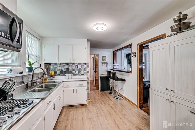1072 Salem Ave, Hillside, NJ 07205 - kitchen with stainless steel appliances, light wood-style floors, white cabinetry, and backsplash