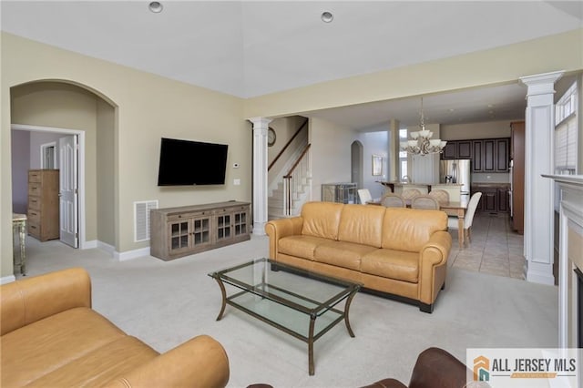 living area with arched walkways, a notable chandelier, visible vents, light carpet, and stairs