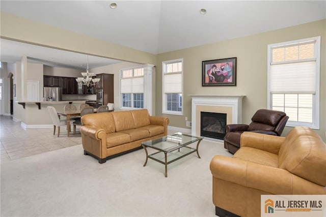 living room with a notable chandelier, light tile patterned flooring, plenty of natural light, and lofted ceiling