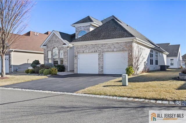 view of front of house with a garage, a front lawn, and central air condition unit