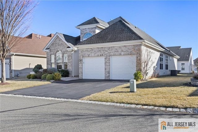 view of front of property with a garage, driveway, brick siding, and a front lawn