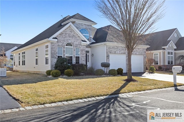 view of front of property featuring brick siding, a front yard, central AC, a garage, and driveway