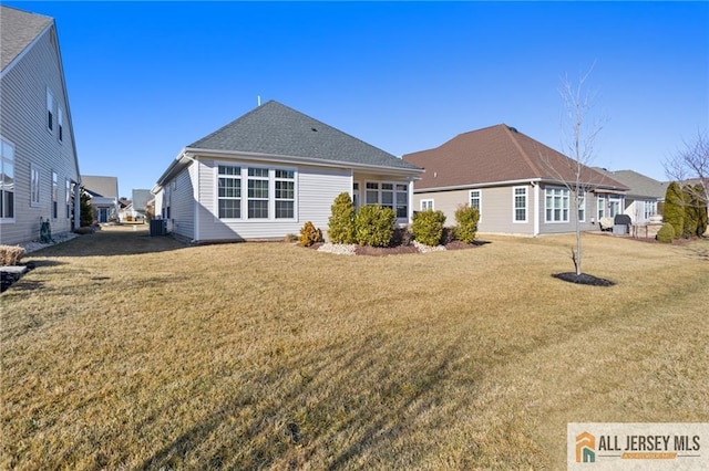 rear view of property with central AC and a yard