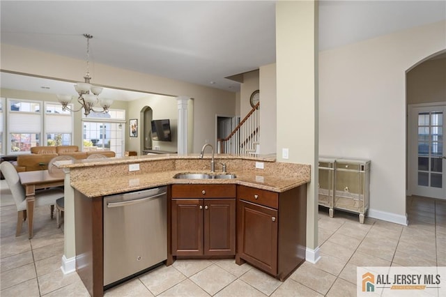 kitchen featuring a peninsula, light stone countertops, a notable chandelier, stainless steel dishwasher, and a sink