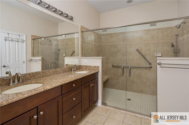 bathroom featuring a stall shower, double vanity, a sink, and tile patterned floors