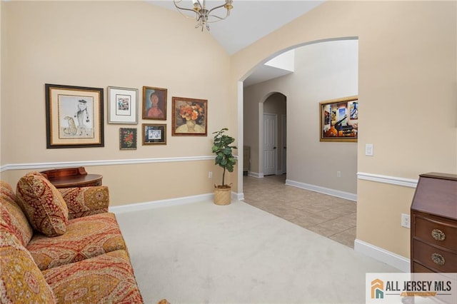 carpeted living area with arched walkways, vaulted ceiling, and baseboards