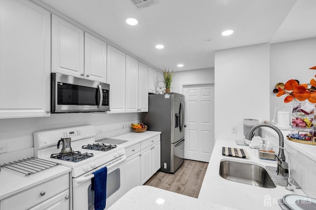 358 Rector St Unit 218, Perth Amboy, NJ 08861 - kitchen with white cabinets, stainless steel appliances, visible vents, a sink, and light wood-style floors