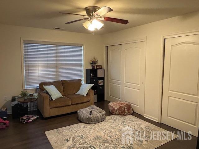 living area featuring a ceiling fan and dark wood finished floors