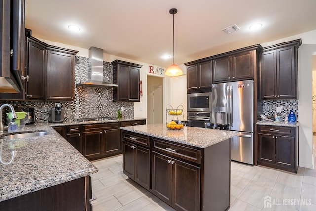 kitchen with stainless steel appliances, wall chimney exhaust hood, a sink, backsplash, and dark brown cabinetry