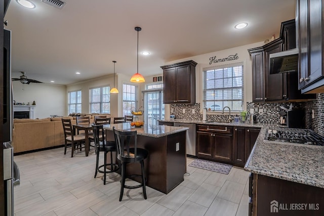 kitchen with a fireplace, ceiling fan, decorative backsplash, stone counters, and open floor plan