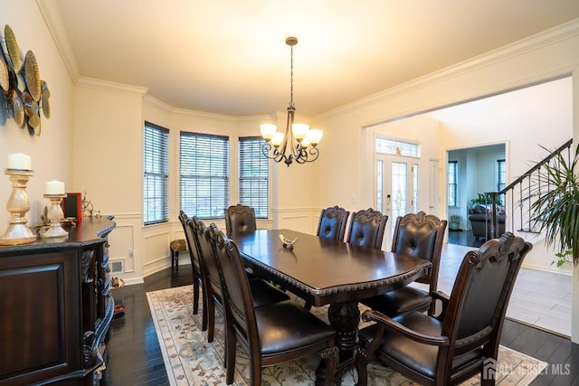 dining area featuring a chandelier, dark wood-type flooring, plenty of natural light, ornamental molding, and wainscoting